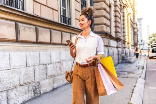 woman using a mobile phone and carrying shopping bags - fashion stock pictures, royalty-free photos & images