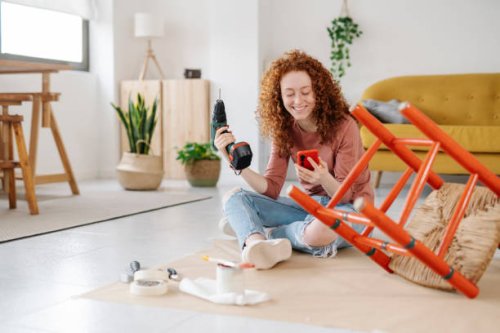 woman using a mobile phone while renovating and repairing an old chair. - home decoration stock pictures, royalty-free photos & images
