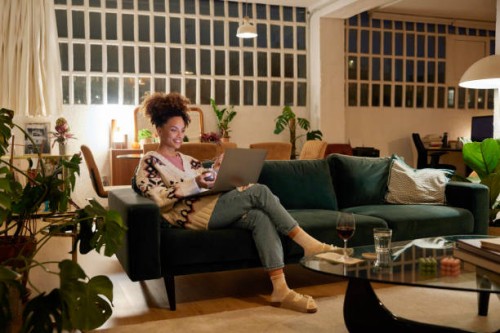 woman using laptop on sofa in living room - home decoration stock pictures, royalty-free photos & images