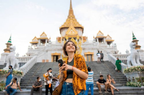 woman using smartphone standing on the background of wat traimit - travel stock pictures, royalty-free photos & images