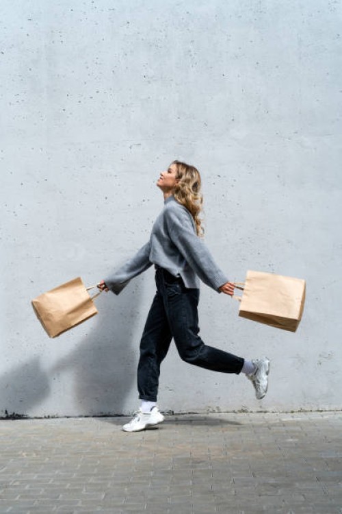 woman walking along street with two shopping bags - fashion stock pictures, royalty-free photos & images