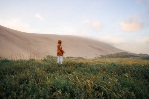 woman walking among big sand dunes during extreme weather - fashion stock pictures, royalty-free photos & images