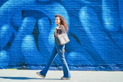 woman walking outdoors on the street. portrait of young woman with curly hair walking outdoors on the street against colorful wall. urban concept. - fashion stock pictures, royalty-free photos & images