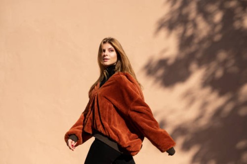 woman walking past a wall with shadow of a tree - fashion stock-fotos und bilder