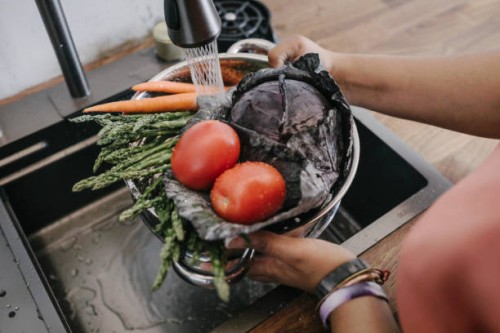 woman washing fresh vegetable in sink at home - food stock-fotos und bilder