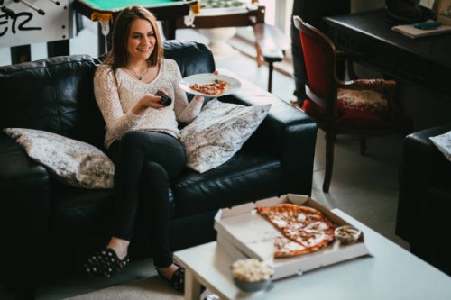 woman watching tv and and eating take-out pizza at home - junk food stock pictures, royalty-free photos & images