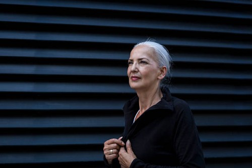 woman wearing black tracksuit top in front of black background - fashion photos et images de collection
