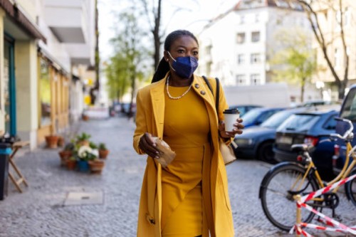 woman wearing mask walking in the city holding a take away food and coffee - junk food stock pictures, royalty-free photos & images