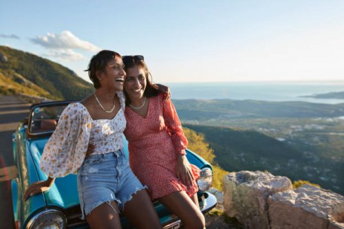 woman with arm around female friend leaning on car - travel stock pictures, royalty-free photos & images