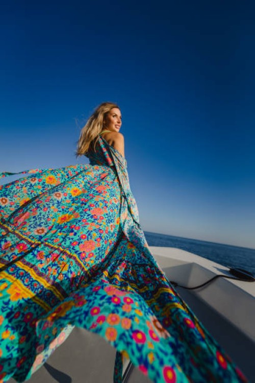 woman with flowing dress standing against clear blue sky - fashion stock pictures, royalty-free photos & images