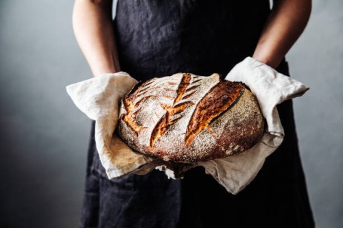 woman with fresh baked sourdough bread in kitchen - food stock pictures, royalty-free photos & images