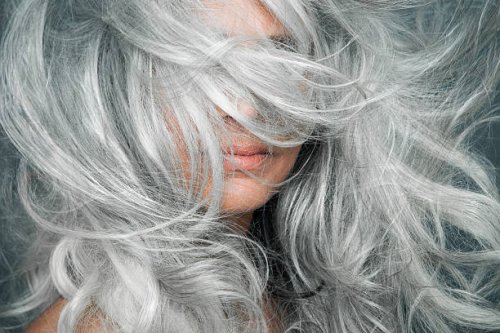 woman with grey hair blowing across her face. - hairstyle stock-fotos und bilder