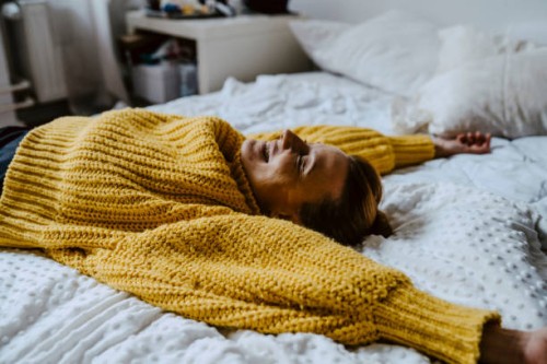 woman with hand raised lying on bed at home - home decoration stock pictures, royalty-free photos & images