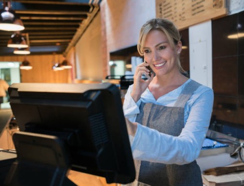 woman working at a bakery talking to a customer on smartphone and registering the takeout on the system - junk food stock pictures, royalty-free photos & images