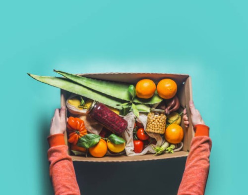 women hands in red sweatshirt holding eco-friendly paper shopping box with various healthy groceries - food stock pictures, royalty-free photos & images