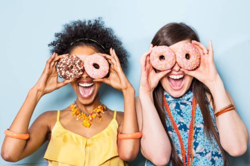 women holding doughnuts in front of eyes. - food stock pictures, royalty-free photos & images
