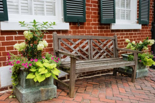 wood bench and potted plants outside of brick house - garden decoration stock pictures, royalty-free photos & images