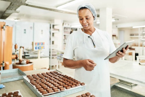 worker using a digital tablet in a commercial chocolate making factory - food stock pictures, royalty-free photos & images