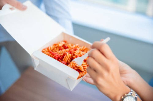 working and taking a bite from her colleague's take out lunch - junk food stock pictures, royalty-free photos & images