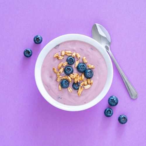 yogurt with berries and cereal on purple colored background. overhead view - food stock pictures, royalty-free photos & images