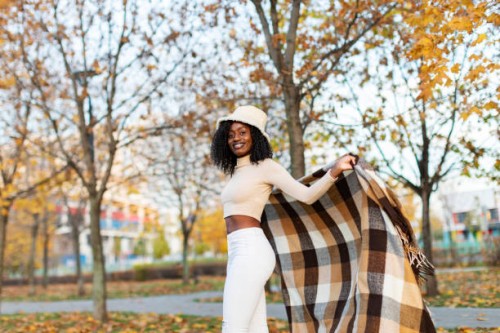 young adult black female in poncho relaxing in autumn park - fashion stock pictures, royalty-free photos & images