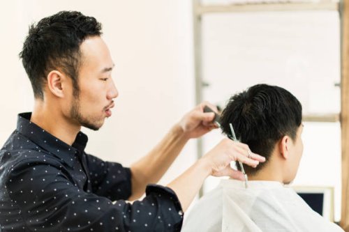 young adult male hair stylist owner cutting man's hair - hairstyle stock pictures, royalty-free photos & images