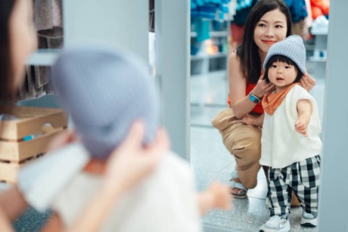 young asian mother shopping with her toddler in clothing store - fashion stock pictures, royalty-free photos & images