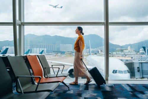 young asian woman carrying suitcase, walking by the window at airport terminal. young asian female traveller waiting for boarding at airport. business travel. travel and vacation concept - travel stock pictures, royalty-free 