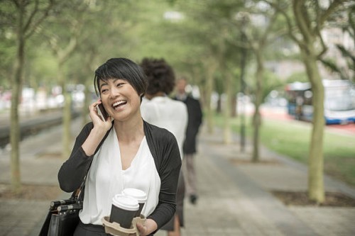 young asian woman carrying takeaway coffee and talking on the phone - junk food stock pictures, royalty-free photos & images