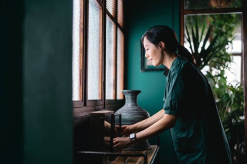 young asian woman decorating and arranging picture frames and home decorations over the cabinet at home. enjoying her time at cozy home - home decoration stock pictures, royalty-free photos & images