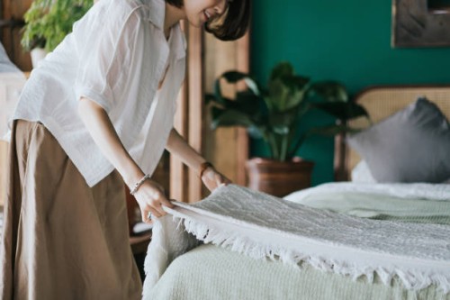 young asian woman doing her morning routine, making up her bed at home. let's get the day started - home decoration stockfoto's en -beelden