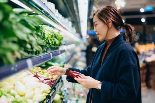young asian woman grocery shopping in supermarket, choosing fresh organic fruits and vegetables along the produce aisle. fruits and vegetables shopping. routine shopping. zero waste. healthy eating diet and go green lifestyle