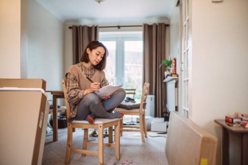 young asian woman moved into her new house and checking the list of new flat pack furniture - home decoration stock pictures, royalty-free photos & images