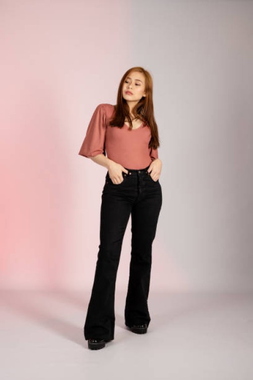 young asian woman posing in a studio shot with her hands in her pants pocket looking away - fashion stock pictures, royalty-free photos & images