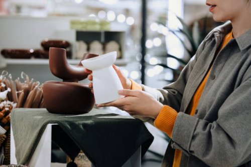 young asian woman shopping for home decorations in a lifestyle homeware store, looking at ceramic plant pot on the display. lifestyle, retail and shopping concept - home decoration stock pictures, royalty-free photos & images