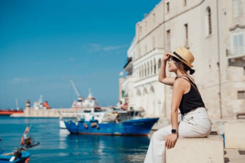 young asian woman sitting at the pier in a seaside town in italy - travel stock-fotos und bilder