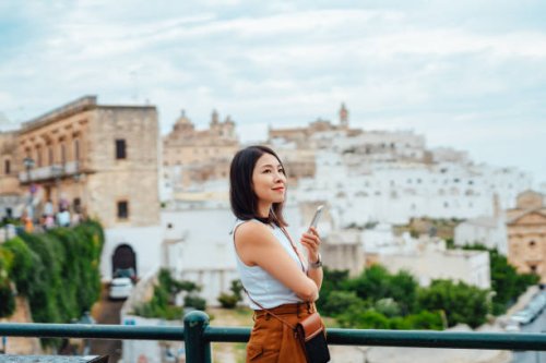 young asian woman using smart phone while overlooking the old town in ostuni, puglia, italy. - travel stockfoto's en -beelden