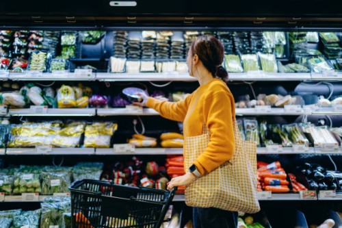 young asian woman with shopping cart, carrying a reusable shopping bag, shopping for fresh organic fruits and vegetables in supermarket. environmentally friendly concept. zero waste and plastic free. eco friendly shopping. su