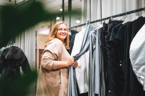 young beautiful woman plus size chooses clothes at store - fashion stock pictures, royalty-free photos & images