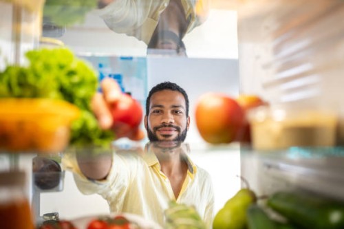 young black man grabbing food from his refrigerator - food stock pictures, royalty-free photos & images