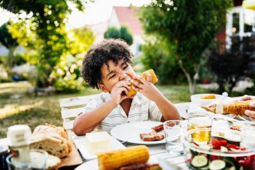young boy eating barbecued corn on the cob - food stock pictures, royalty-free photos & images