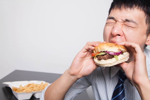 young businessman enjoying a burger - junk food stock pictures, royalty-free photos & images