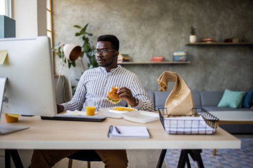 young businessman enjoying burger while taking a break from work at home office - junk food stock pictures, royalty-free photos & images