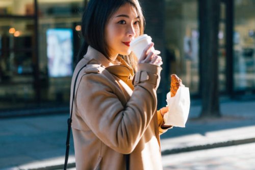 young businesswoman having coffee and croissant on the street - junk food stock pictures, royalty-free photos & images