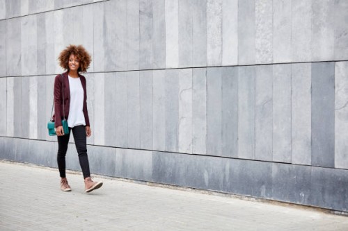 young businesswoman walking on sidewalk by wall - fashion stock pictures, royalty-free photos & images