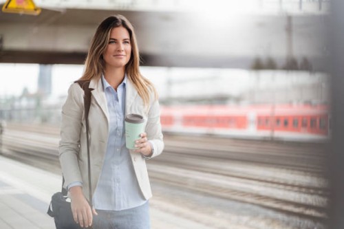 young businesswoman with coffee to go cup, standing on station - junk food stock pictures, royalty-free photos & images