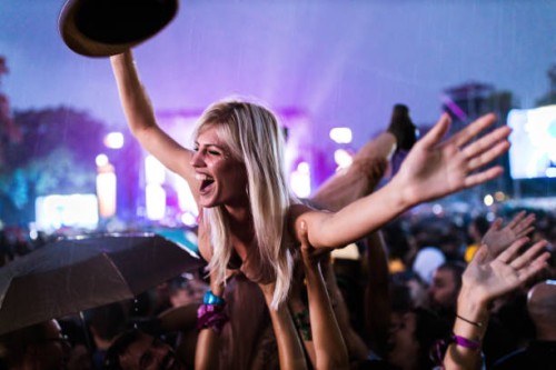 young cheerful woman held by her friends during rainy night on music festival. - concert stock pictures, royalty-free photos & images