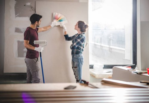 young couple choosing the right color for their wall while renovating apartment. - home decoration stock pictures, royalty-free photos & images