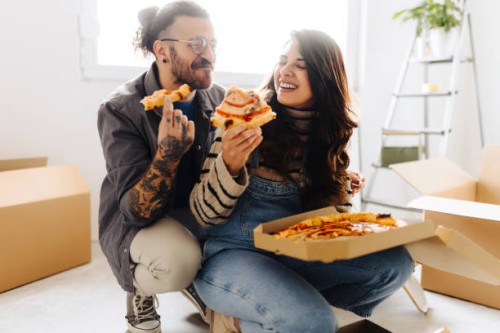 young couple eating pizza in new home - junk food stock pictures, royalty-free photos & images
