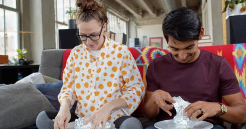 young couple eating take out burritos at home - junk food stock pictures, royalty-free photos & images